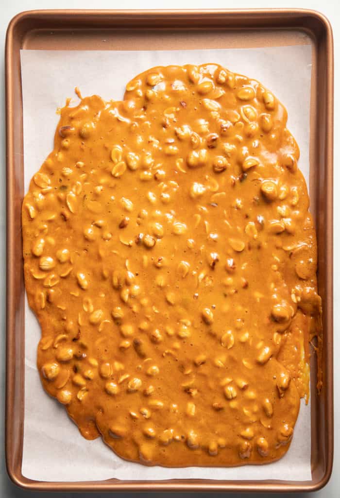 Peanut brittle cooling on a parchment-lined baking sheet