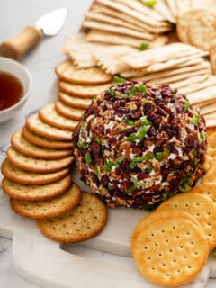 Cranberry goat cheese ball set on a board with crackers around it