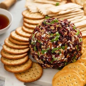 Cranberry goat cheese ball set on a board with crackers around it