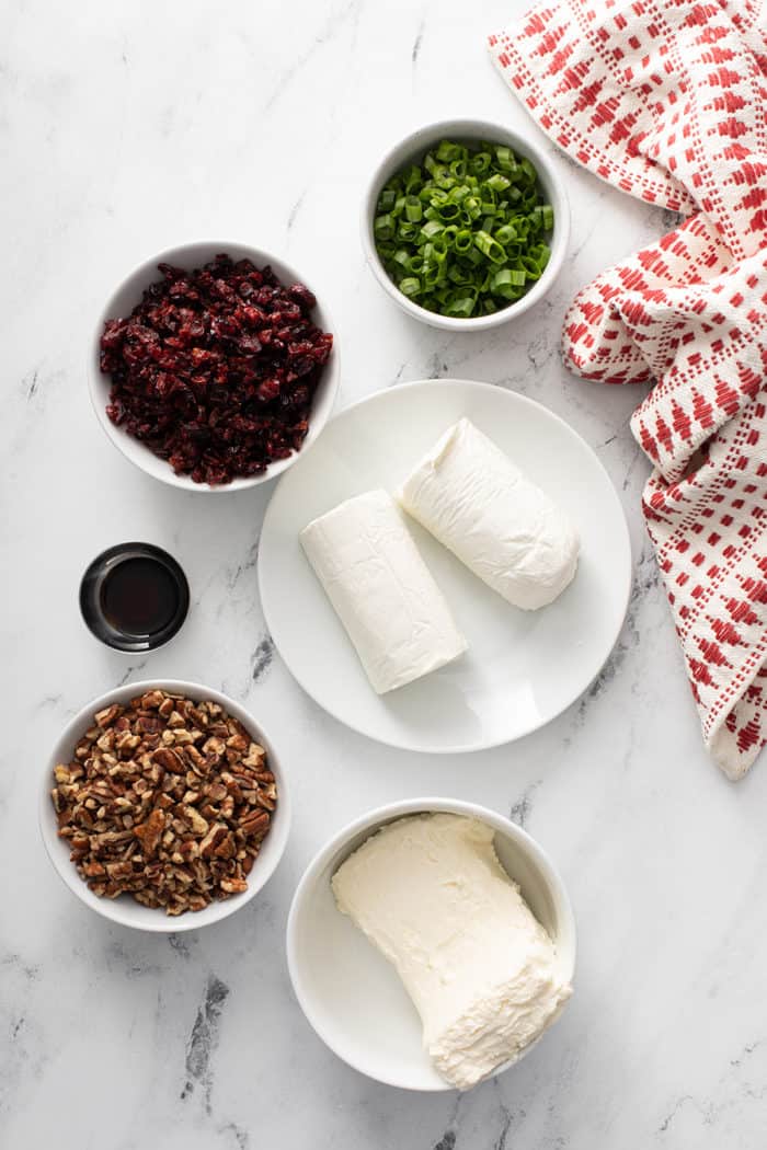 Ingredients for cranberry pecan goat cheese ball arranged on a marble countertop