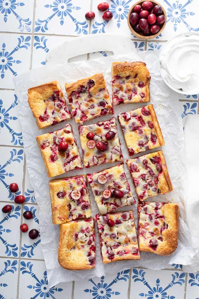 Cut gooey butter bars set on a piece of parchment paper on a tiled counter