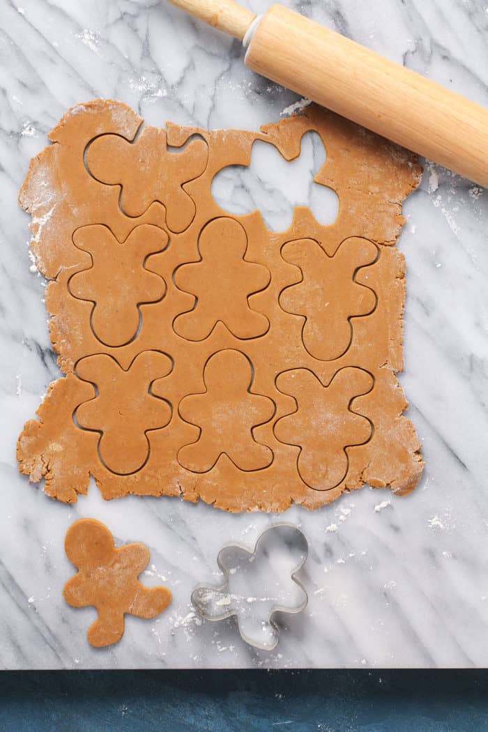 Gingerbread cookie dough rolled out on a marble slab and cut into shapes