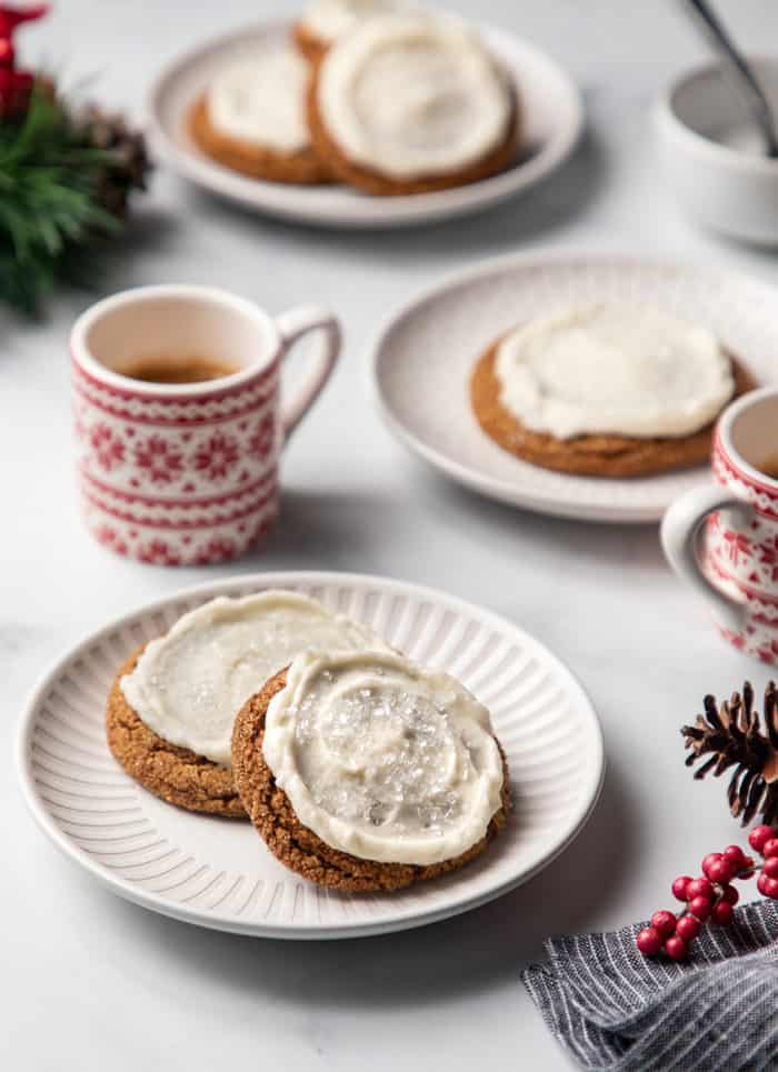 Plates of frosted ginger cookies next to a mug of coffee