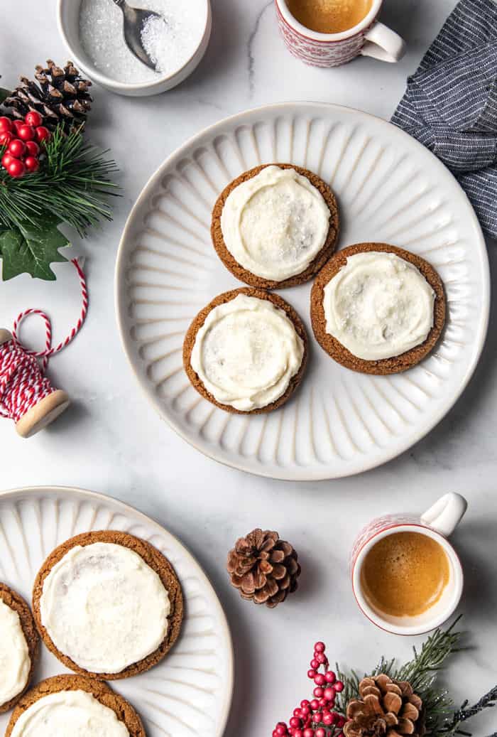 Two white plates with frosted ginger cookies on a white countertop