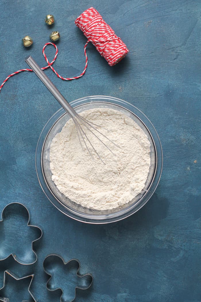 Whisk combining the dry ingredients for gingerbread cookies in a glass mixing bowl