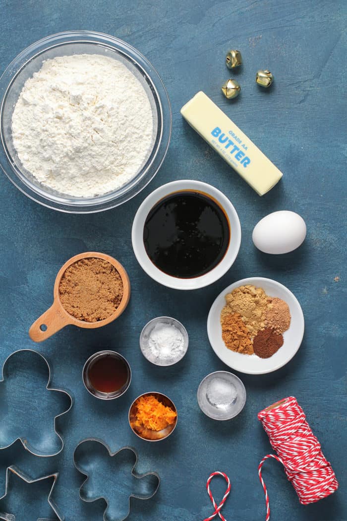 Ingredients for gingerbread cookies arranged on a blue countertop