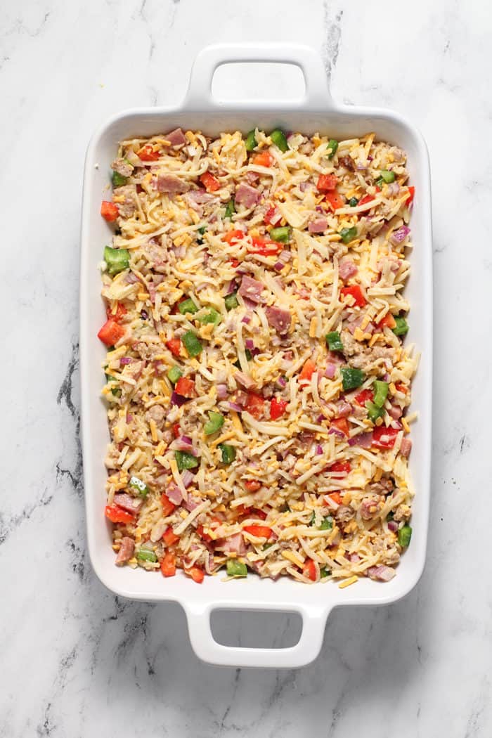 Overhead view of hash brown casserole that's ready to bake in a white baking dish