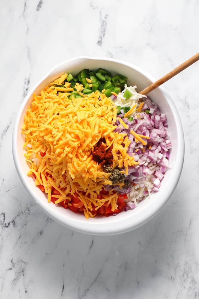 Mix-ins for hash brown breakfast casserole about to be stirred together in a white bowl