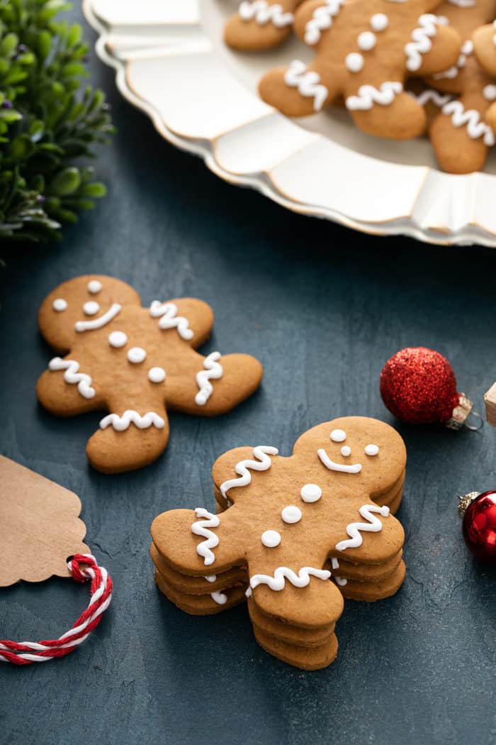 Gingerbread cookies on a blue countertop next to a platter of cookies