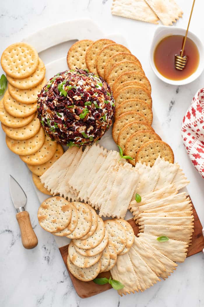 Overhead view of a board spread with an assortment of crackers and a cranberry pecan goat cheese ball
