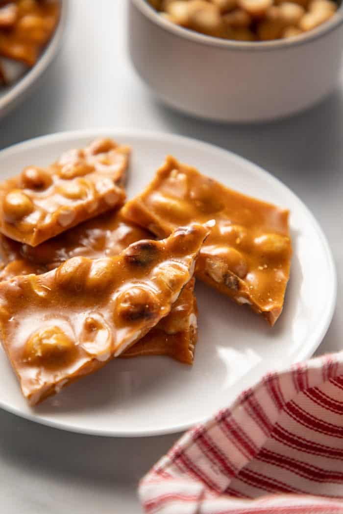 White plate with several pieces of peanut brittle on it