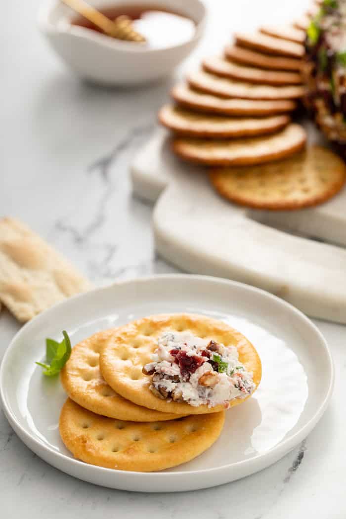 White plate holding crackers, with some cranberry goat cheese ball spread on the top cracker