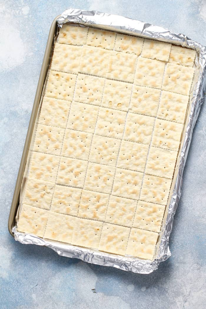 Saltine crackers lined up in a foil-lined sheet pan