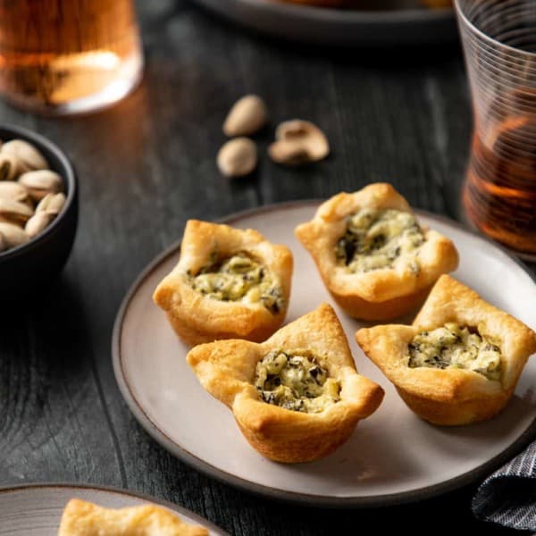 Close up of four spinach artichoke bites on a white plate