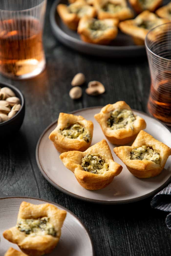 Close up of four spinach artichoke bites on a white plate