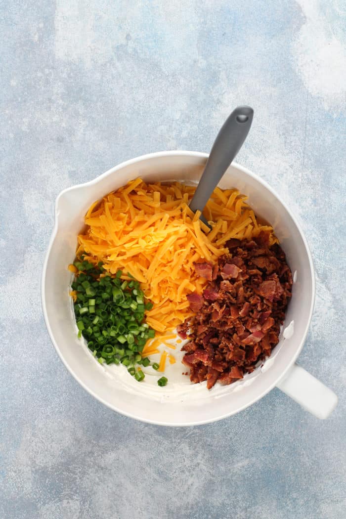 Baked potato dip toppings in a white mixing bowl