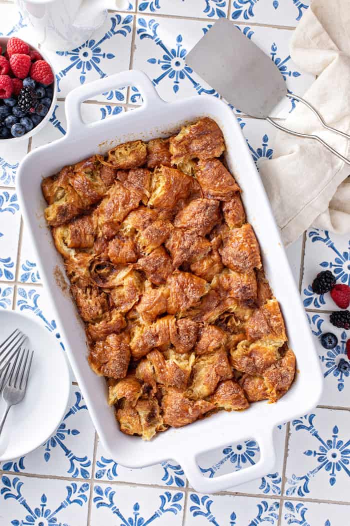Baked croissant bread pudding in a white baking dish on a blue-and-white countertop