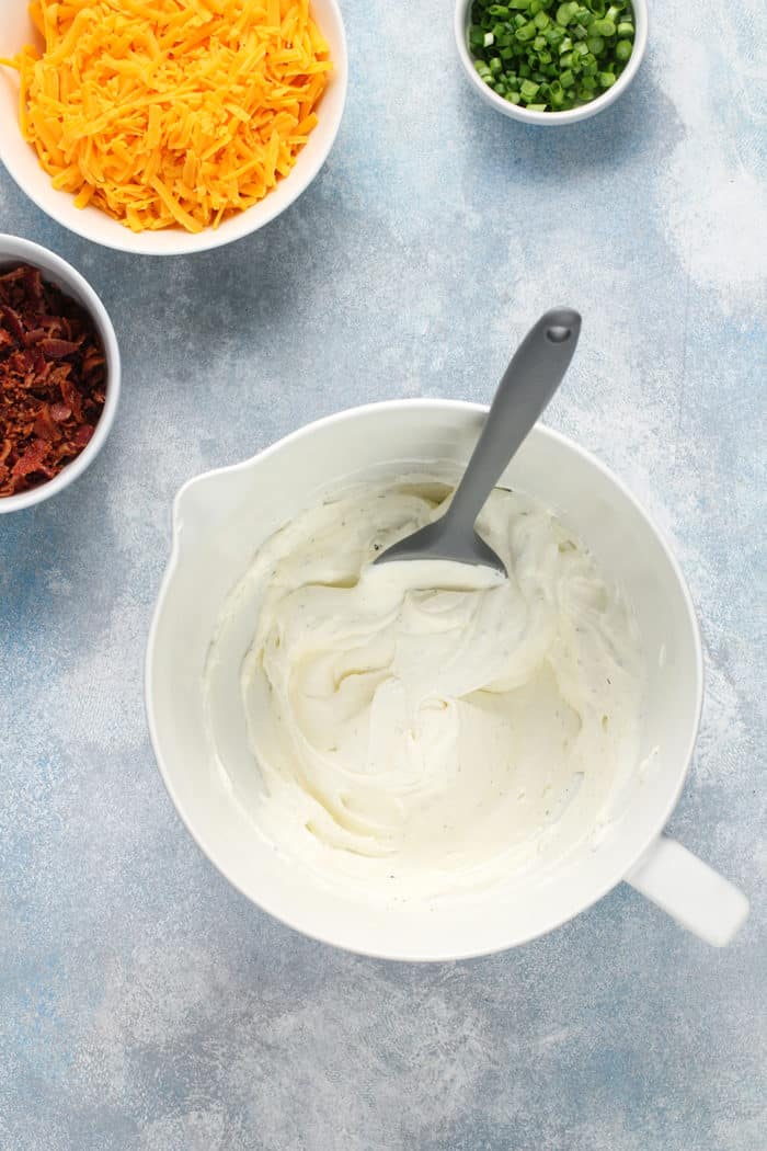 Sour cream and ranch base for baked potato dip in a white mixing bowl