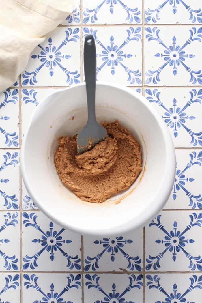 Butter, sugar, and cinnamon mixed together in a white mixing bowl