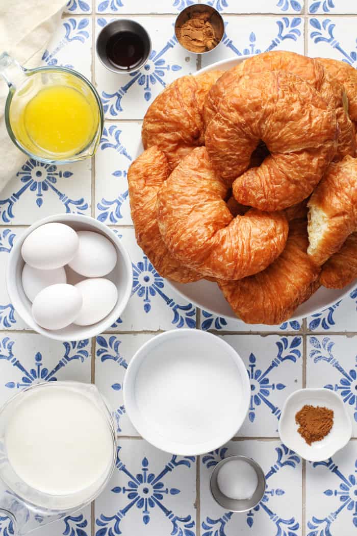 Ingredients for croissant bread pudding arranged on a blue-and-white tiled countertop