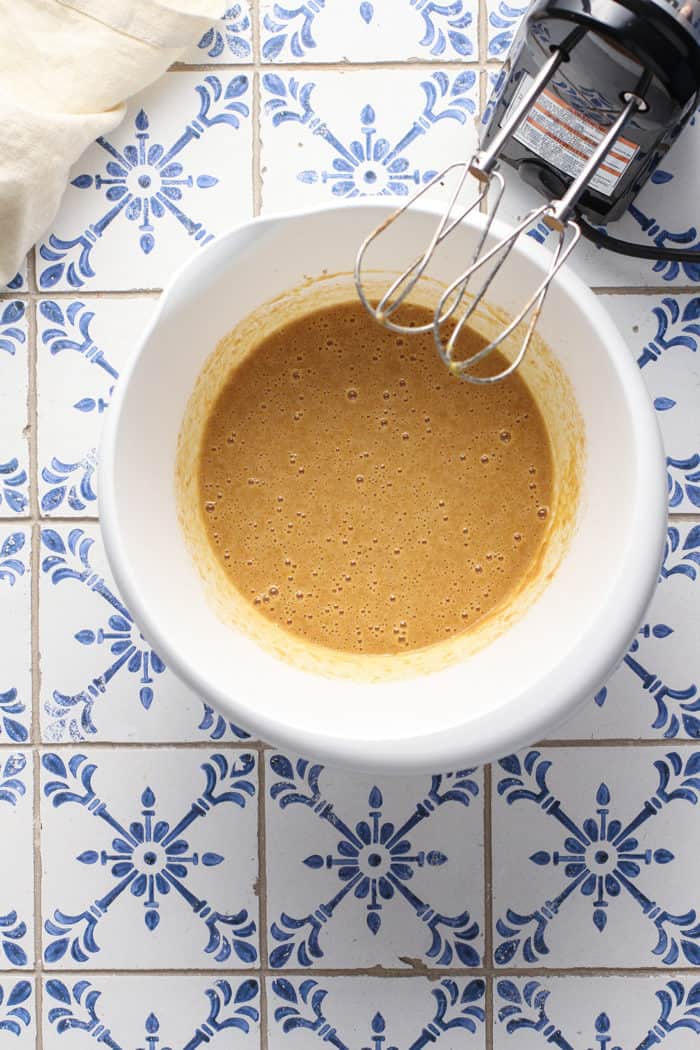 Eggs mixed with butter, sugar, and cinnamon in a white mixing bowl