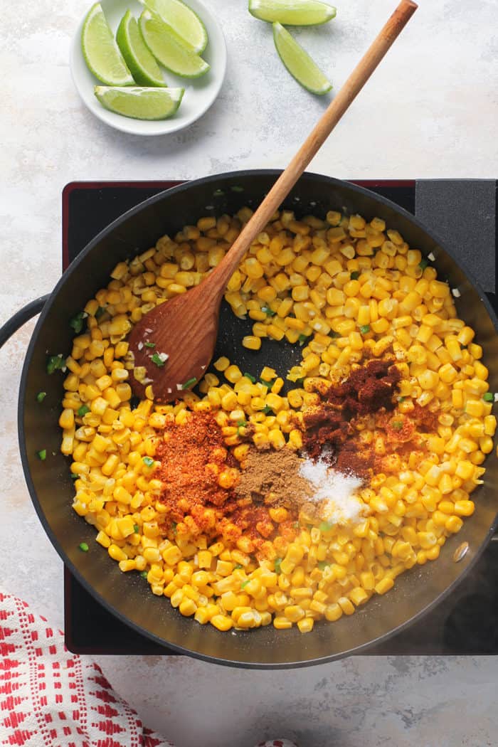 Spices added to sauteed corn in a black skillet