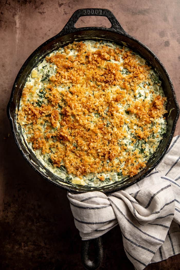Overhead view of spinach artichoke dip in a cast iron skillet, topped with buttery panko topping