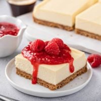 Plated cheesecake bar topped with raspberry sauce