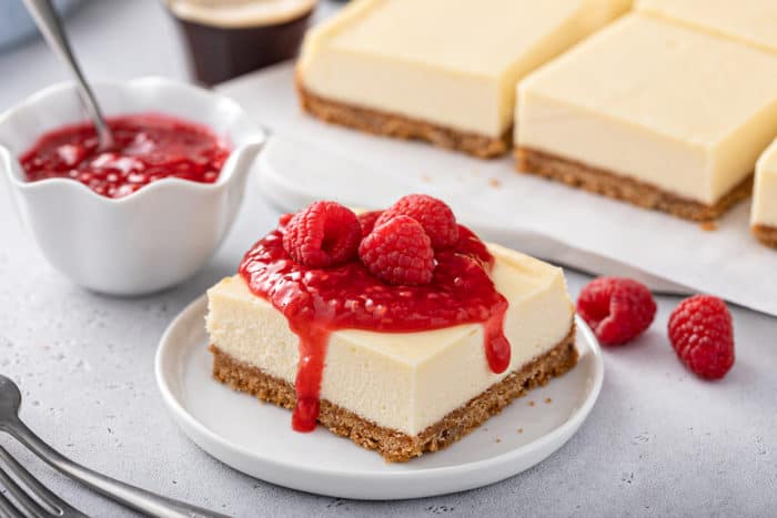 Plated cheesecake bar topped with raspberry sauce