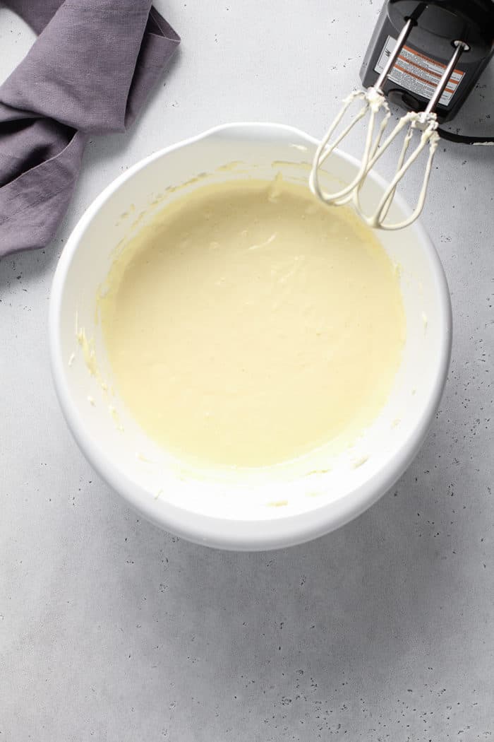 Cheesecake filling base being mixed together in a white mixing bowl