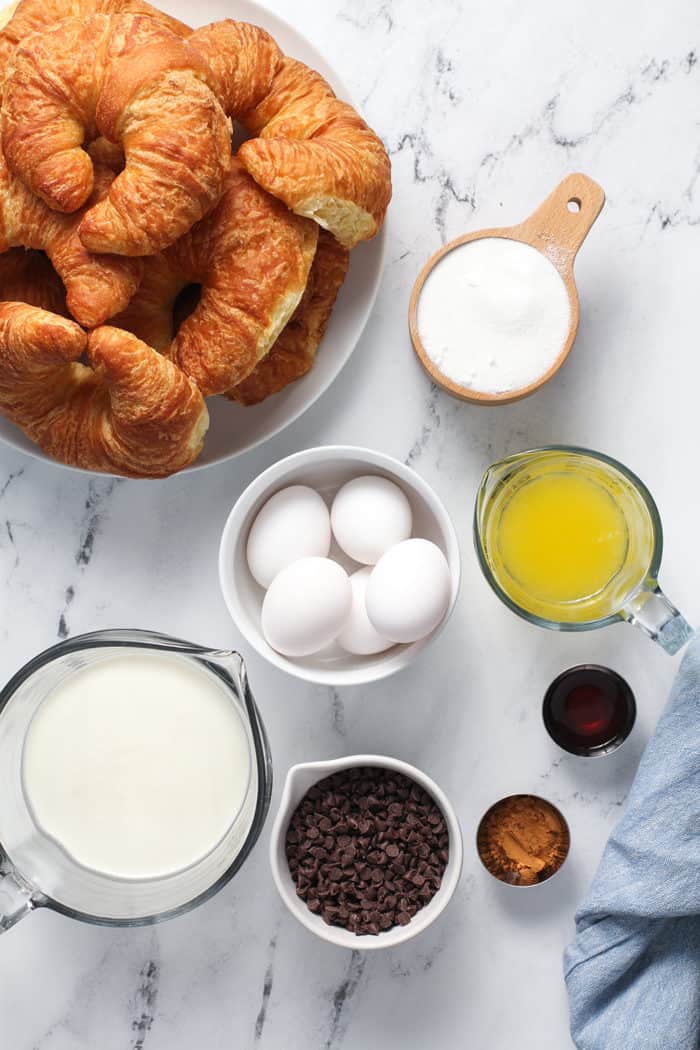 Ingredients for chocolate chip bread pudding arranged on a marble countertop