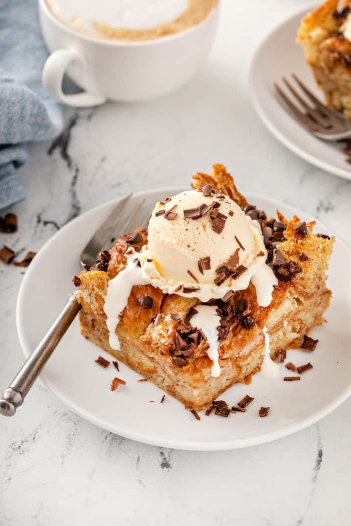 Slice of chocolate chip bread pudding topped with a scoop of vanilla ice cream and chocolate shavings