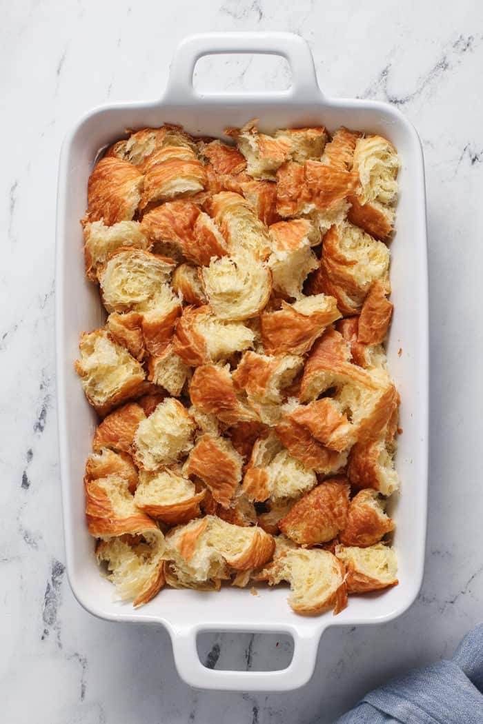 Torn pieces of croissants in a white baking dish