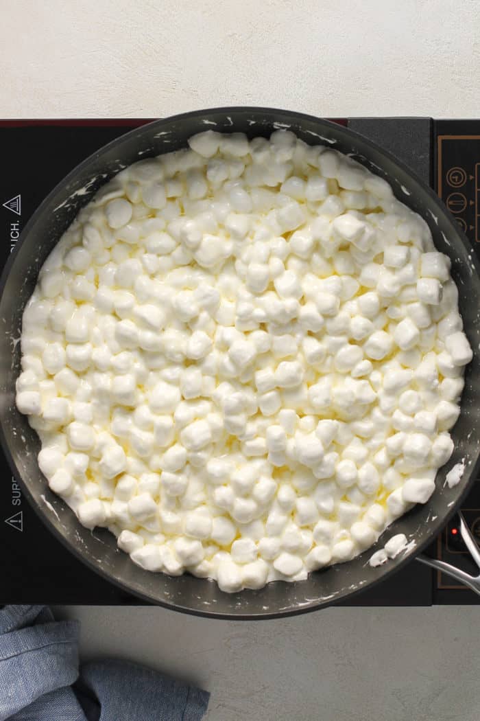Mini marshmallows starting to melt in a black pan