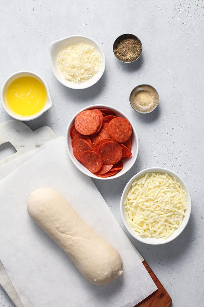 Ingredients for pepperoni bread arranged on a white countertop