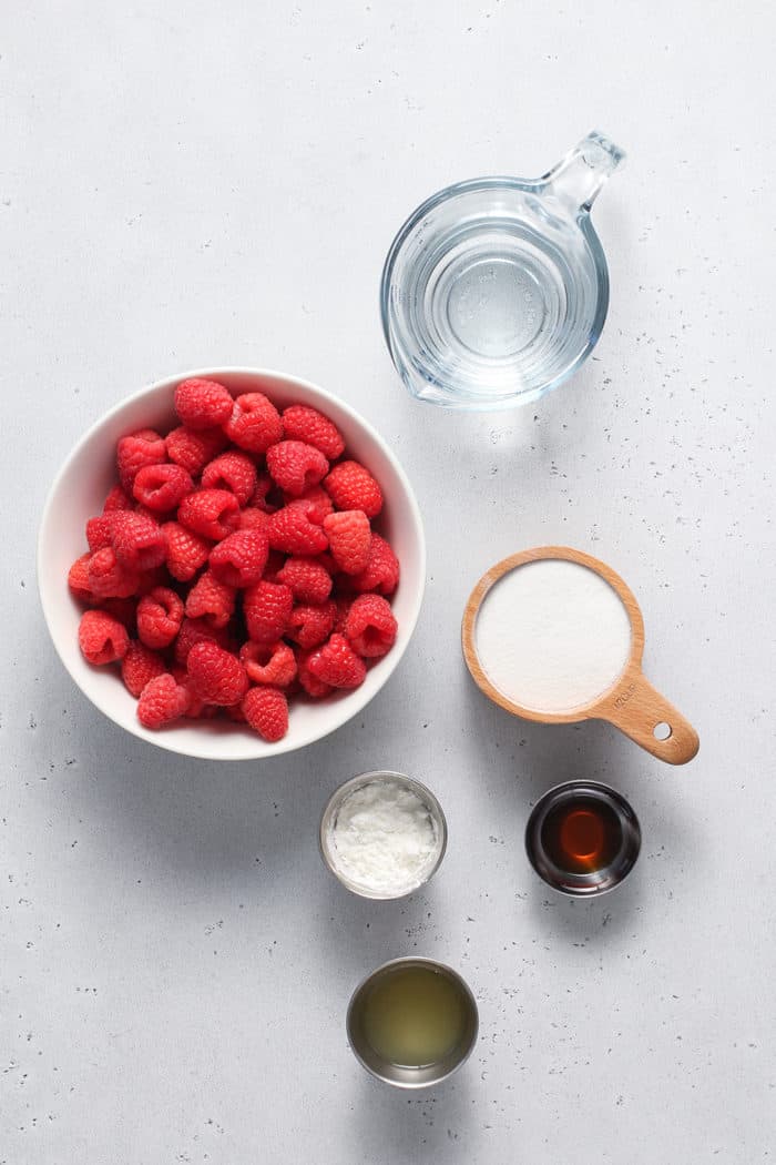 Ingredients for raspberry sauce arranged on a white countertop