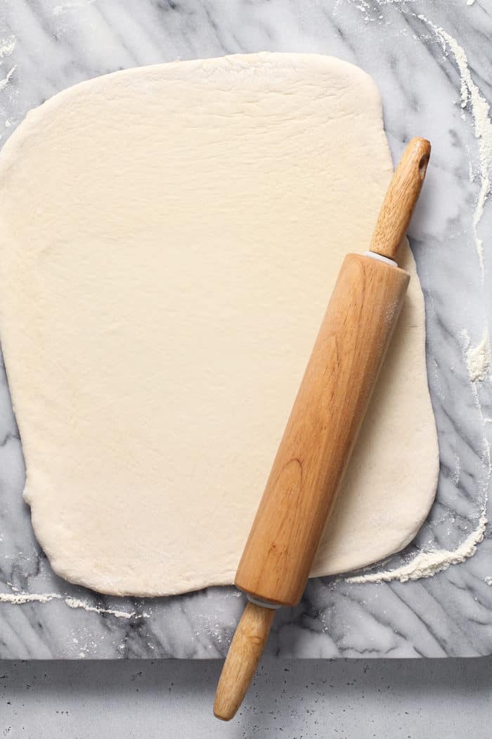 Rolling pin rolling out bread dough into a rectangle