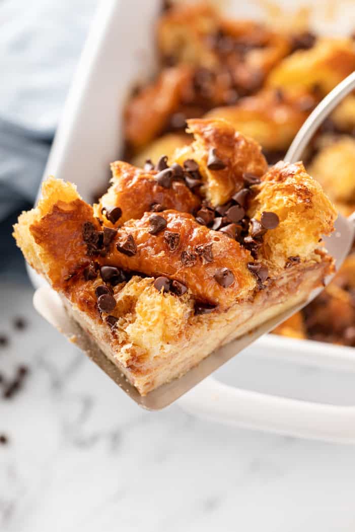 Slice of chocolate chip bread pudding being held up on a cake server