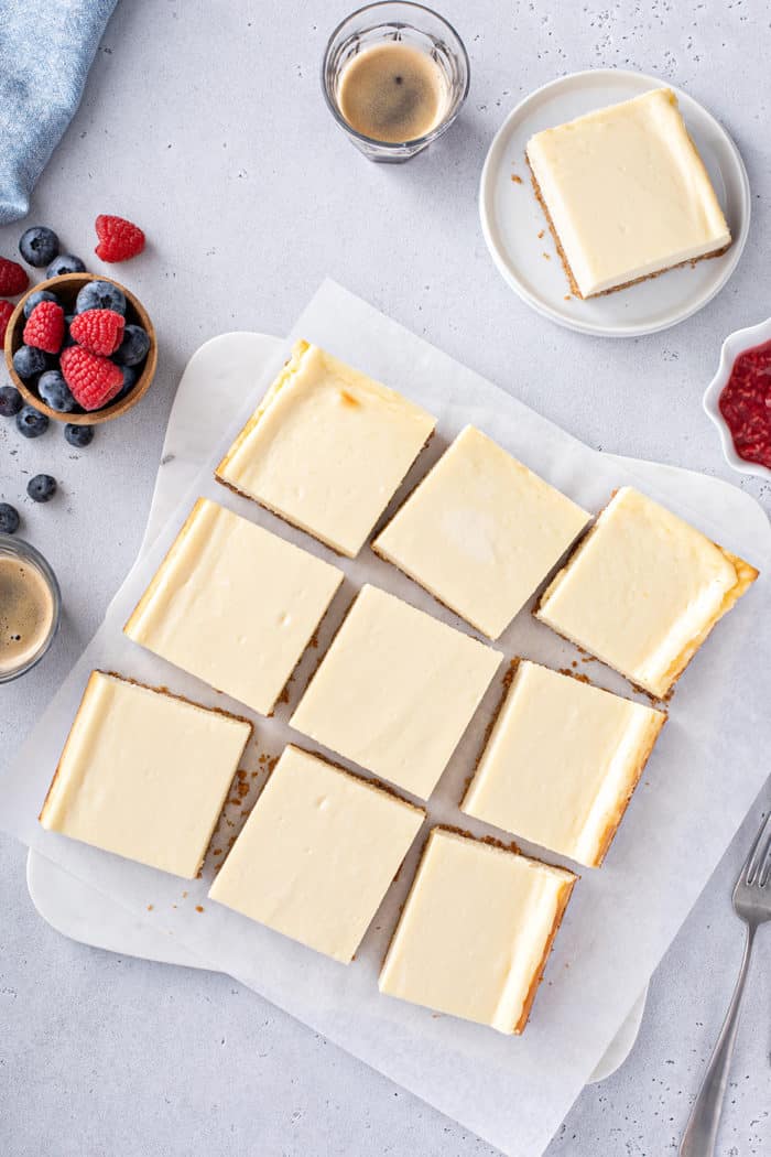 Overhead view of sliced cheesecake bars on parchment paper