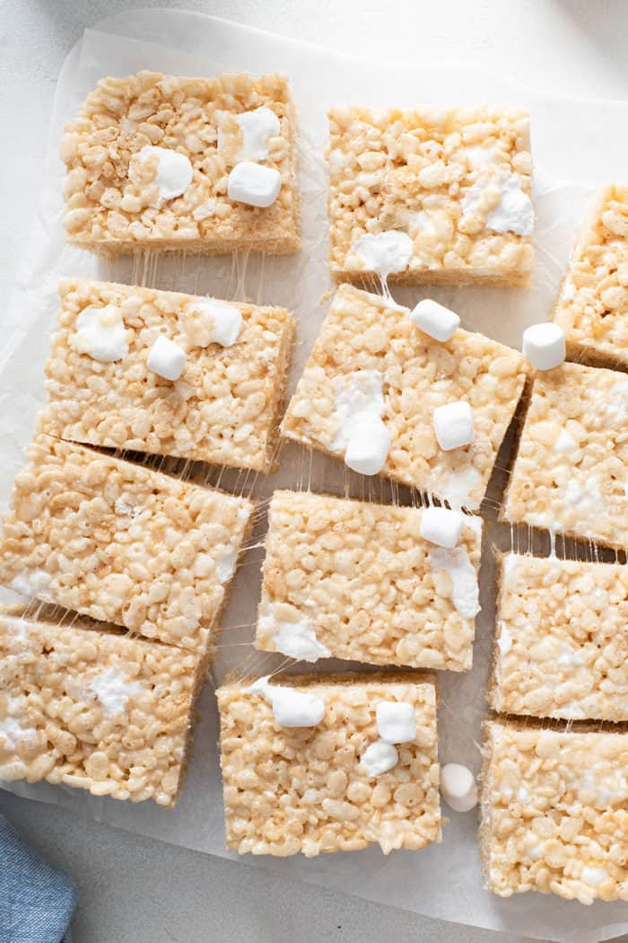 Classic rice krispie treats cut into 12 pieces on a piece of parchment paper