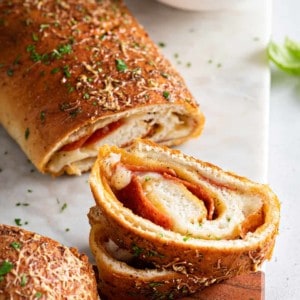 Slices cut from a loaf of pepperoni bread, set next to a bowl of pizza sauce