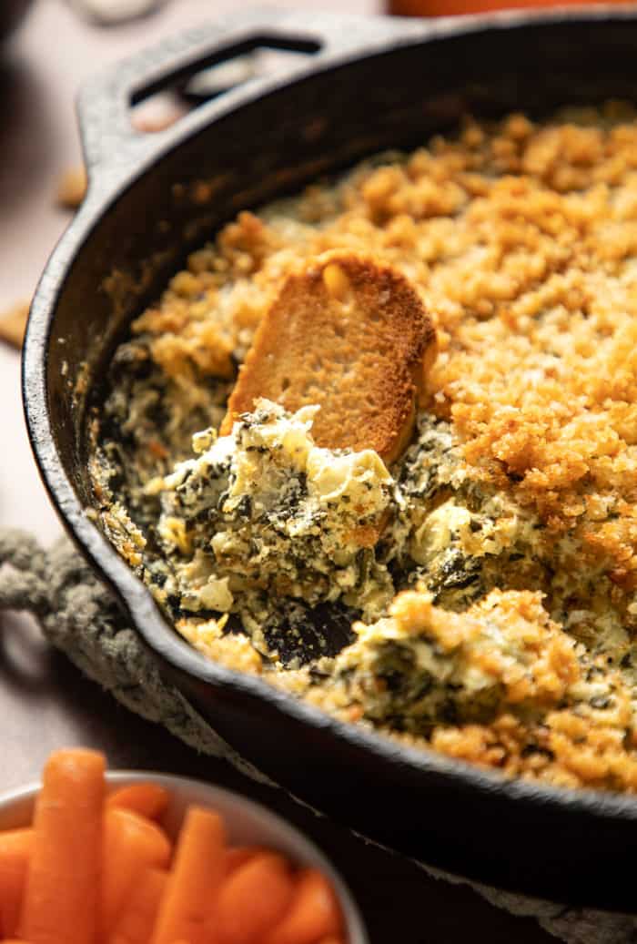 Toasted baguette sliced in a skillet with spinach artichoke dip