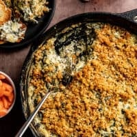 Overhead view of spoon dishing out spinach artichoke dip from a skillet