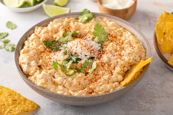 Corn dip in a gray bowl, garnished with cotija cheese, cilantro, and chile lime seasoning