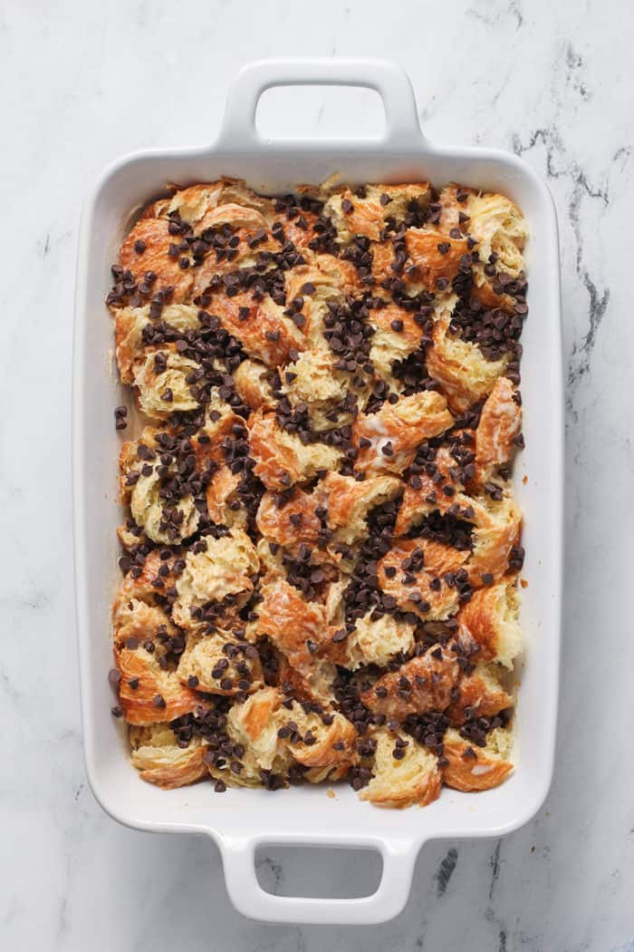 Unbaked chocolate chip bread pudding in a white baking dish, ready to go in the oven