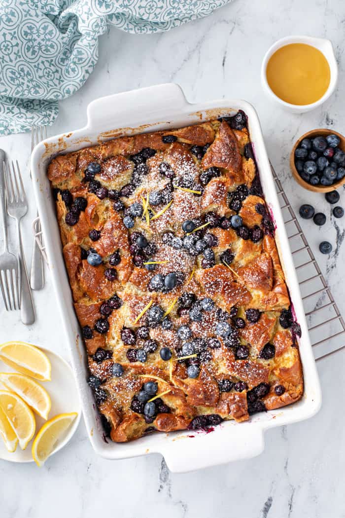 Baked blueberry bread pudding in a white baking dish, set on a wire cooling rack