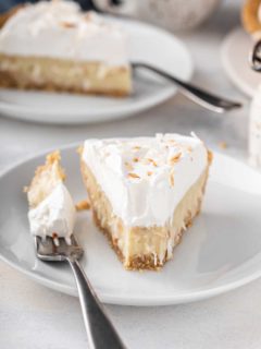 Front view of a plated slice of coconut cream pie with a bite taken from the front