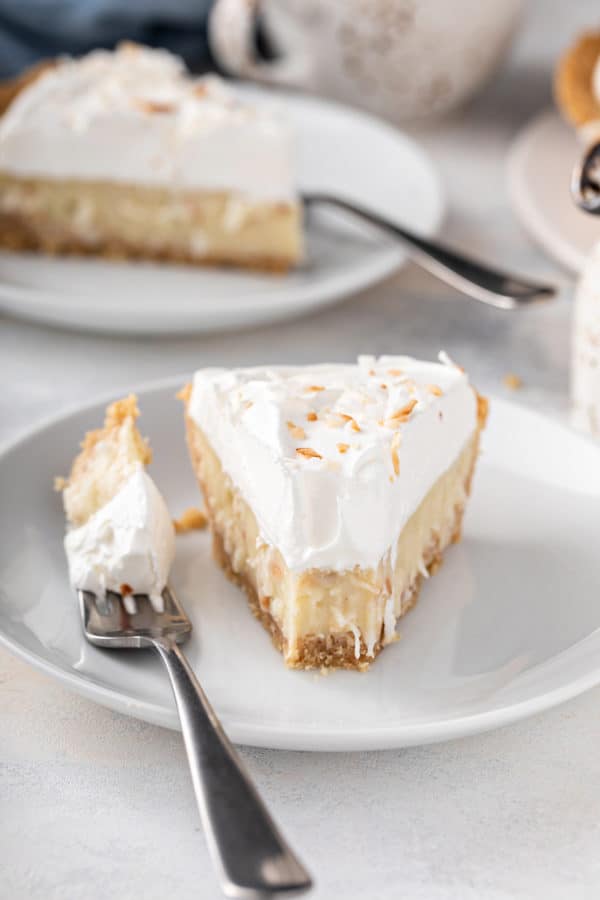 Front view of a plated slice of coconut cream pie with a bite taken from the front