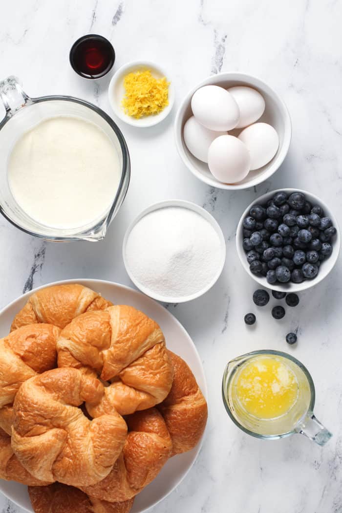 Ingredients for blueberry bread pudding arranged on a marble countertop