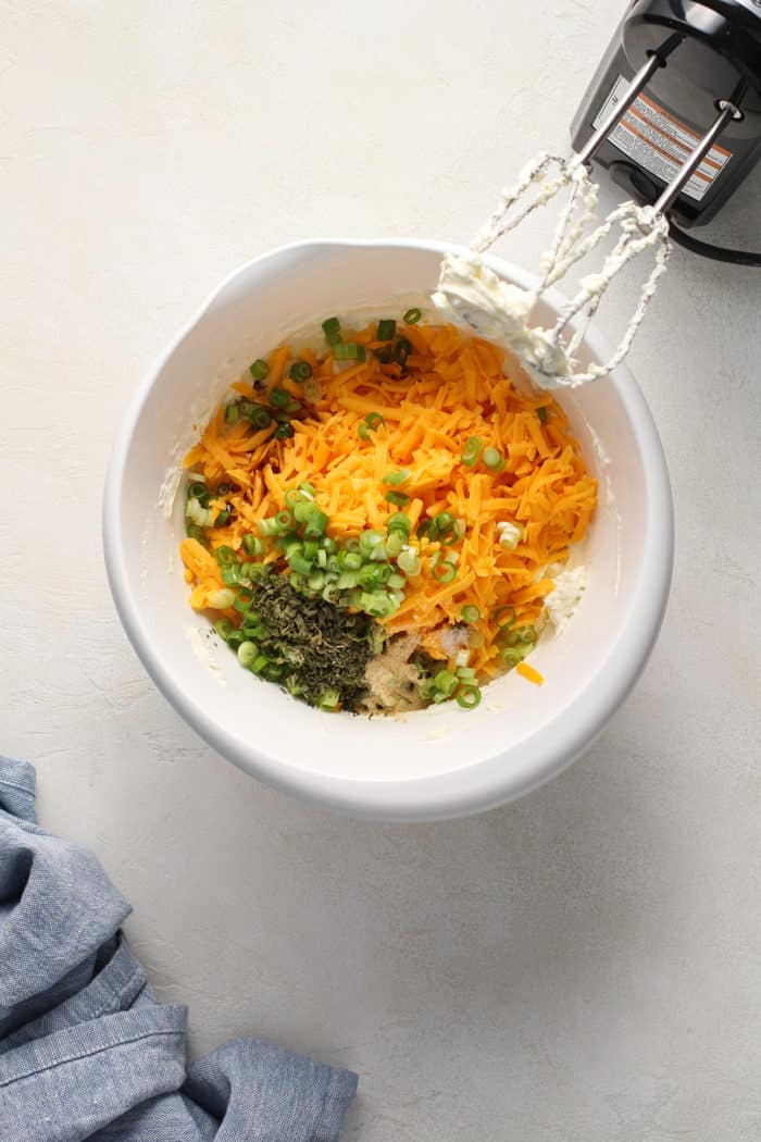 Cheese ball mix-ins about to be beaten into cream cheese in a white mixing bowl